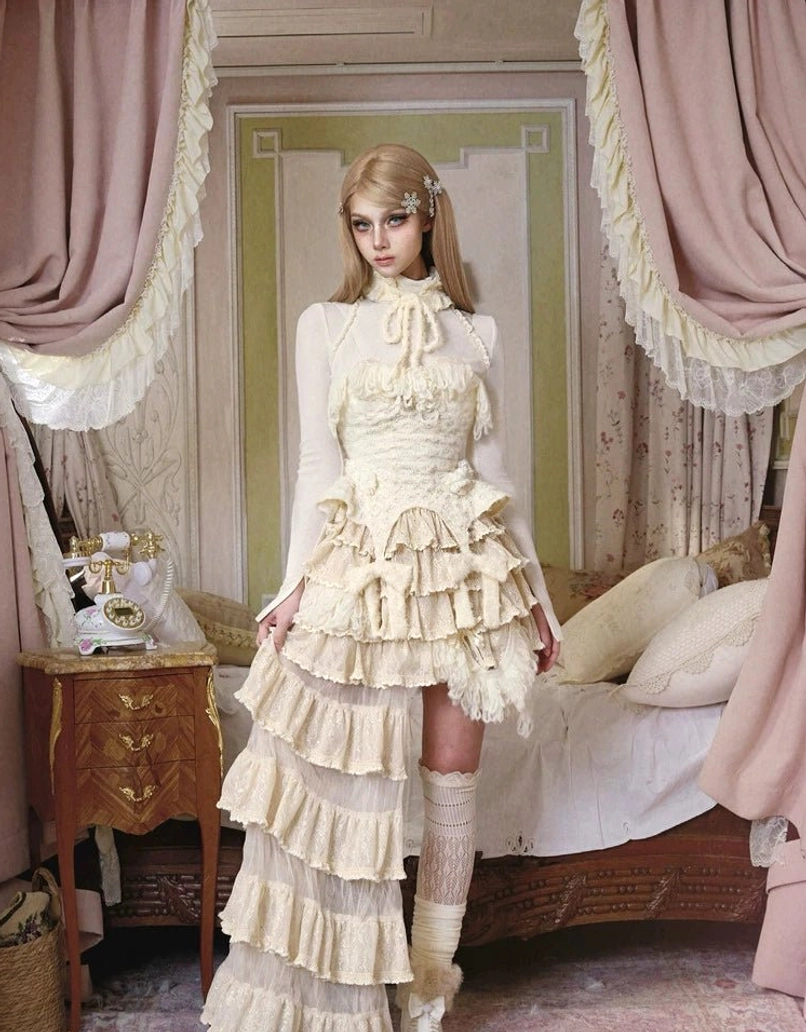 Ivory textured knit corset top worn with an asymmetrical ruffled skirt and high-neck layered styling, full front view