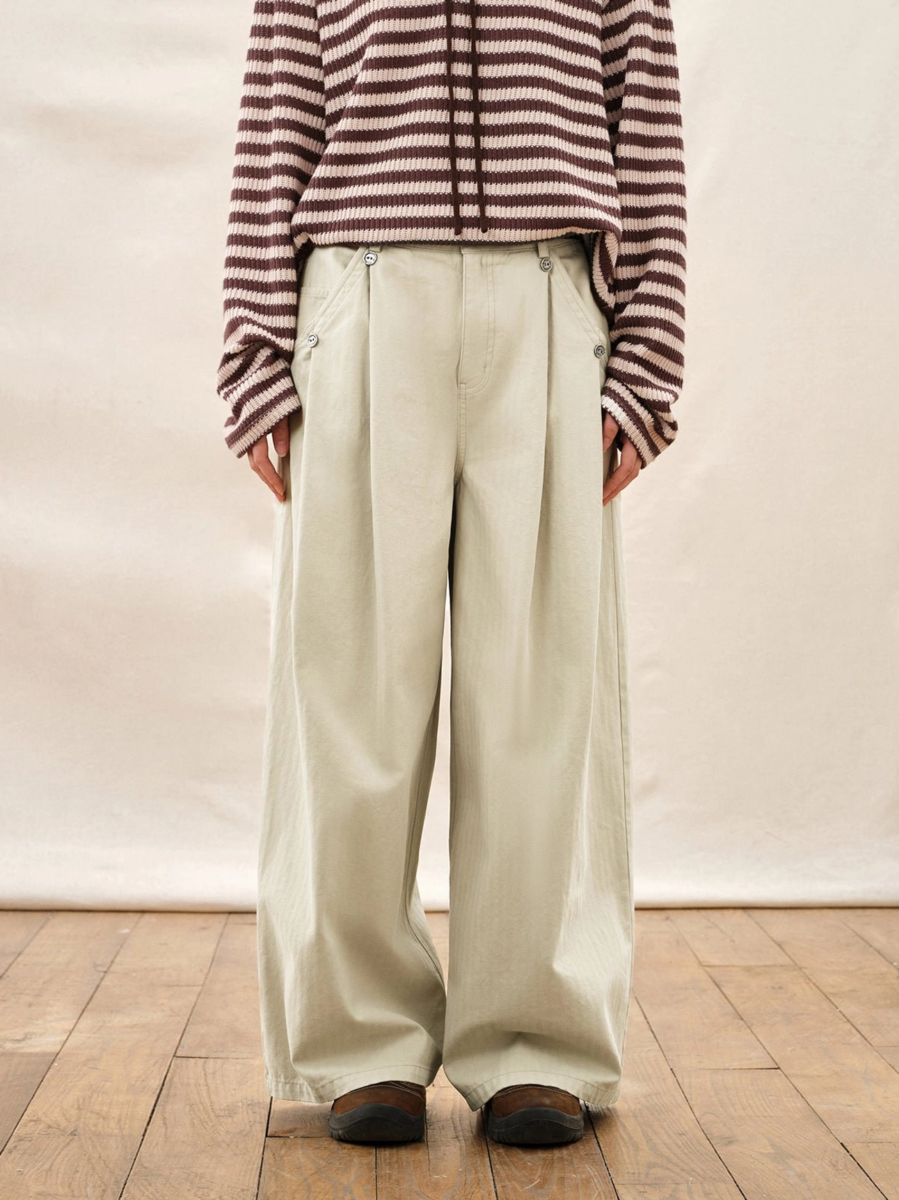 Ivory high waisted pleated wide leg streetwear pants styled with a striped knit top in a full body studio outfit