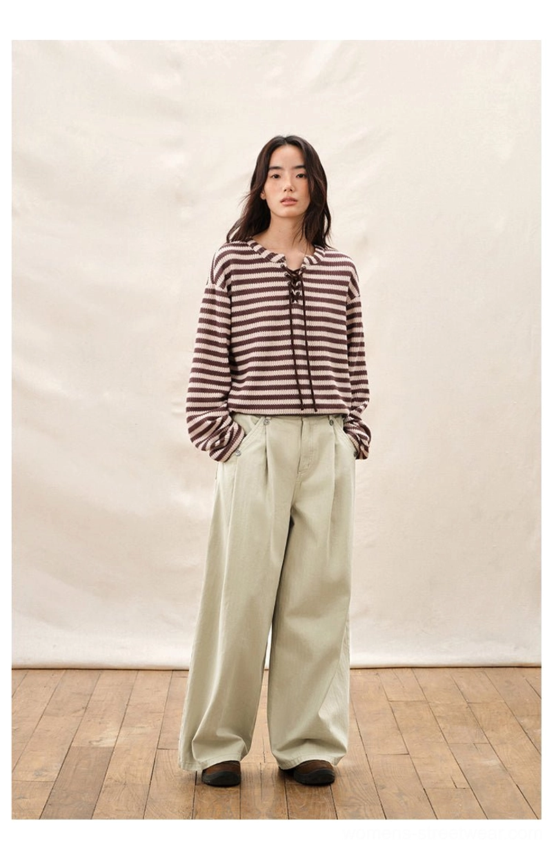 Ivory high waisted wide leg pleated streetwear pants paired with a striped top in a minimalist studio setting