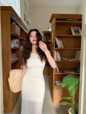 Full body view of an ivory lace maxi dress set with square neckline, fitted floor length silhouette, and sheer floral lace overlay in a vintage interior
