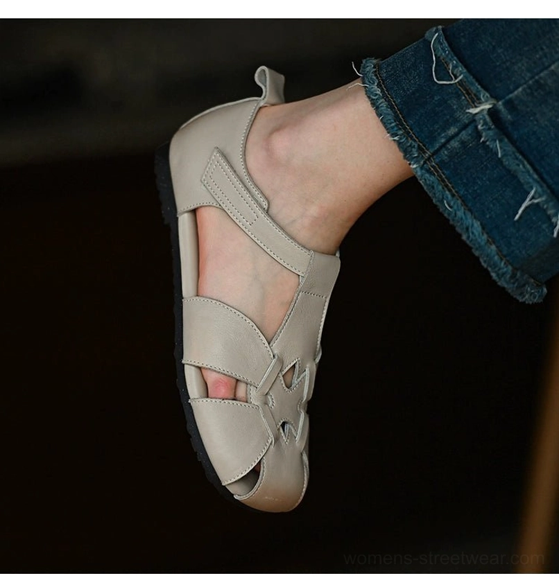 Rear side view of ivory leather cutout sandals worn with cropped denim, featuring a heel pull tab and low flat sole