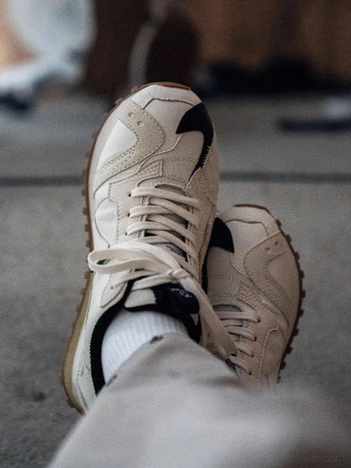 Ivory low-top runner sneakers featuring a deconstructed panel design, black toe cap, padded collar, and rubber outsole