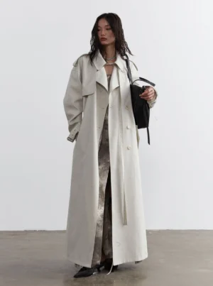 Ivory oversized double-breasted maxi trench coat front full body view styled with a tie-dye dress and black handbag