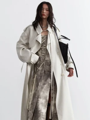 Ivory oversized maxi trench coat close front view showing wide dropped shoulders, epaulets, cuff straps, and layered dress styling