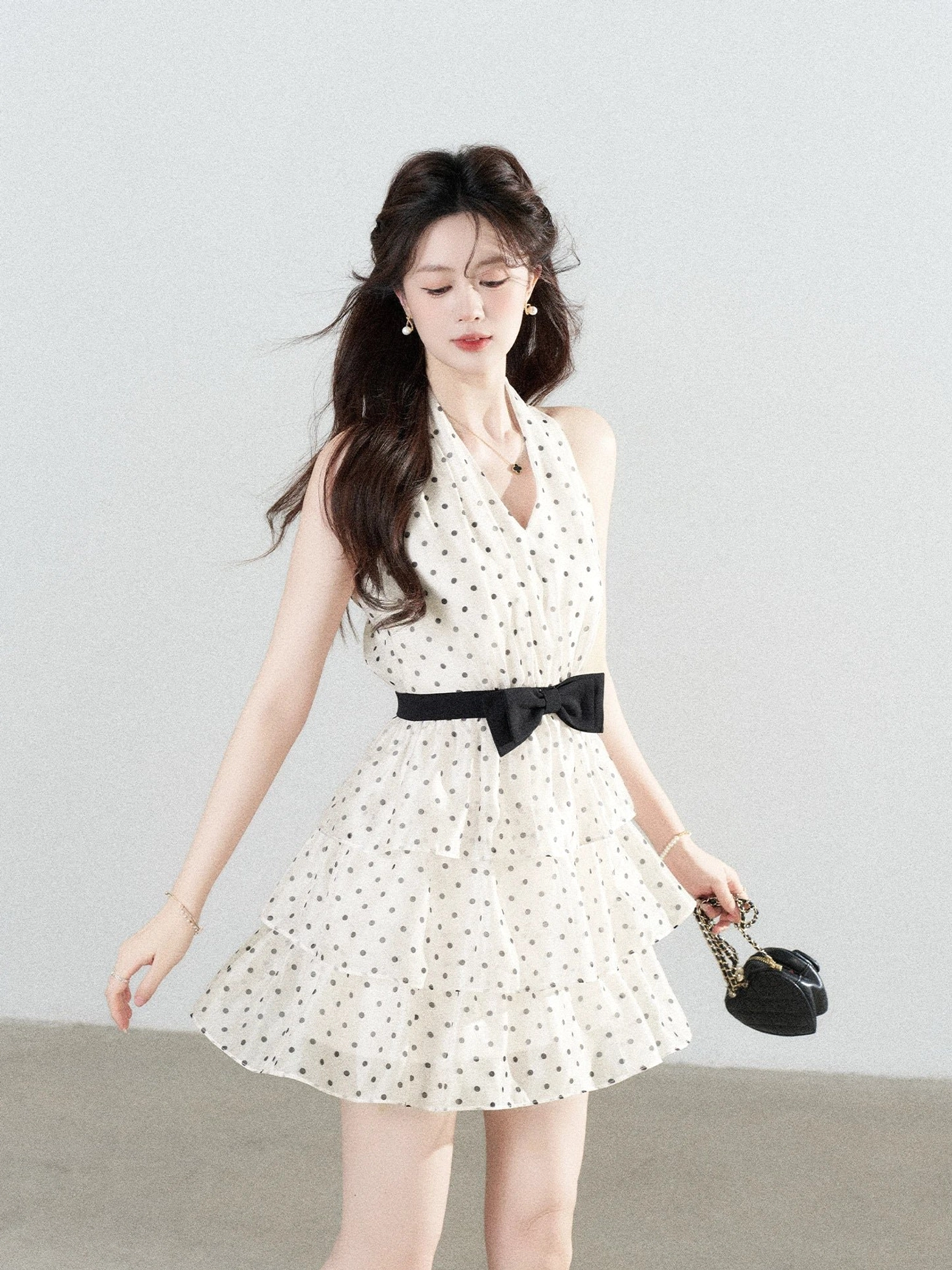 Ivory polka dot bow halter tiered mini dress front view with black waist bow and layered ruffle skirt