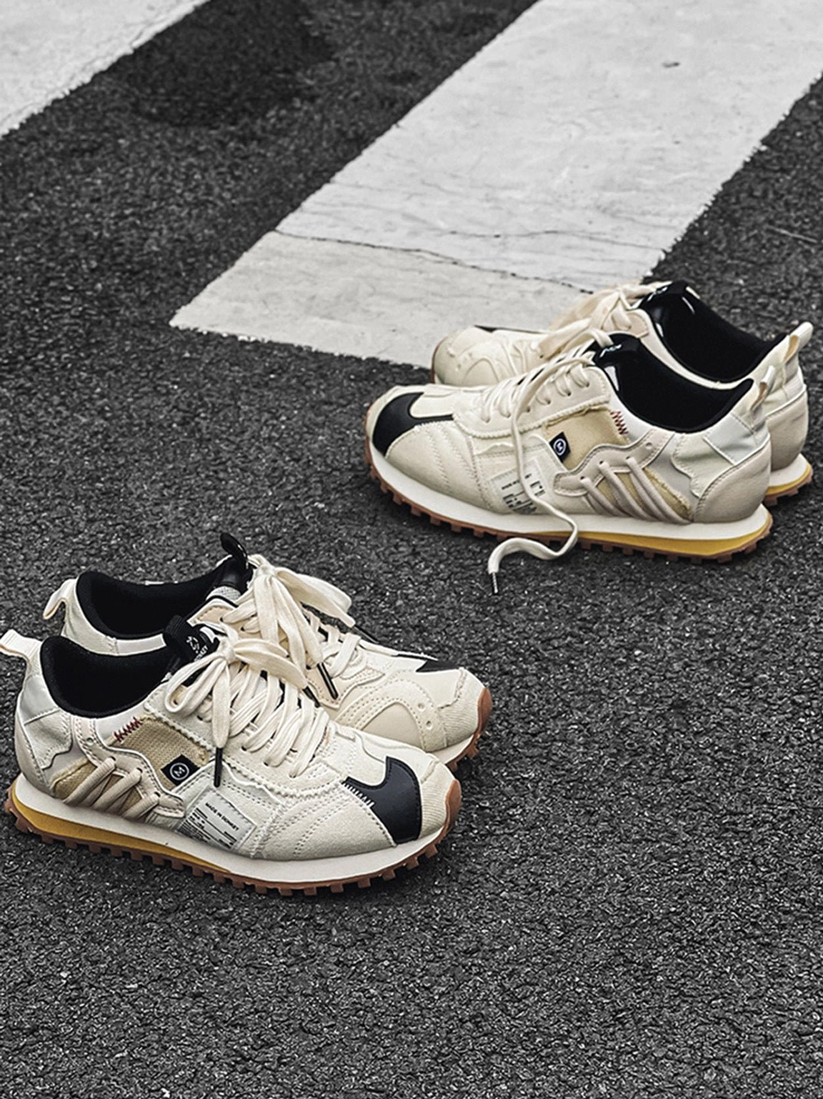 Ivory retro runner sneakers with layered cream panels, black accents, padded collar, and textured gum waffle outsole