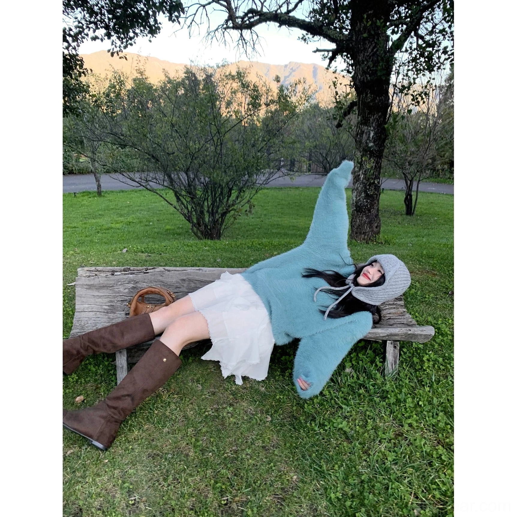 Ivory ruffle mini skirt styled with a blue sweater gray beanie and brown knee high boots in a casual park outfit