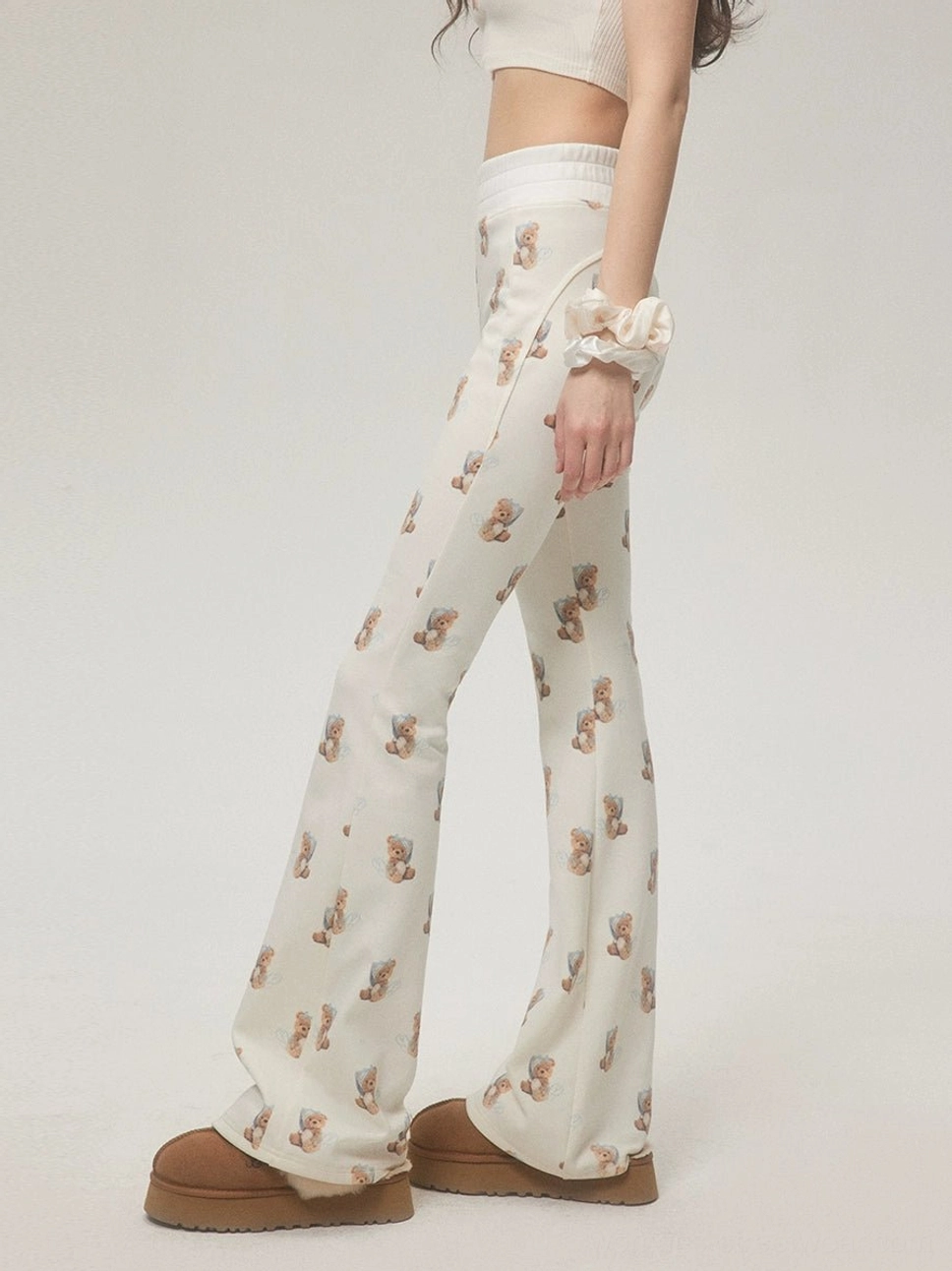 Side view of ivory teddy bear print high-waisted flare pants with elastic waistband and slim flared leg silhouette