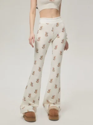 Ivory teddy bear print high-waist flare streetwear pants shown from the front with brown platform ankle boots