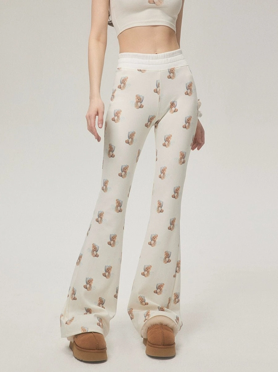 Ivory teddy bear print high-waist flare streetwear pants shown from the front with brown platform ankle boots