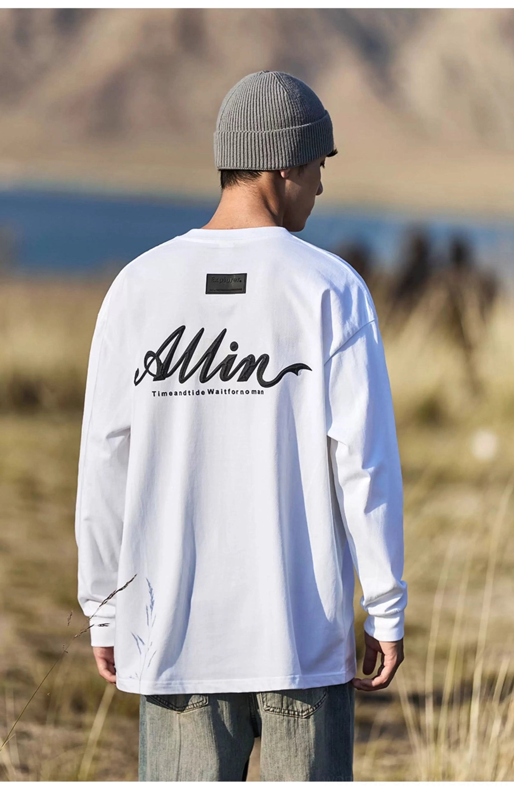 Ivory white oversized alpine script cotton long sleeve tee with black back graphic in alpine outdoor setting