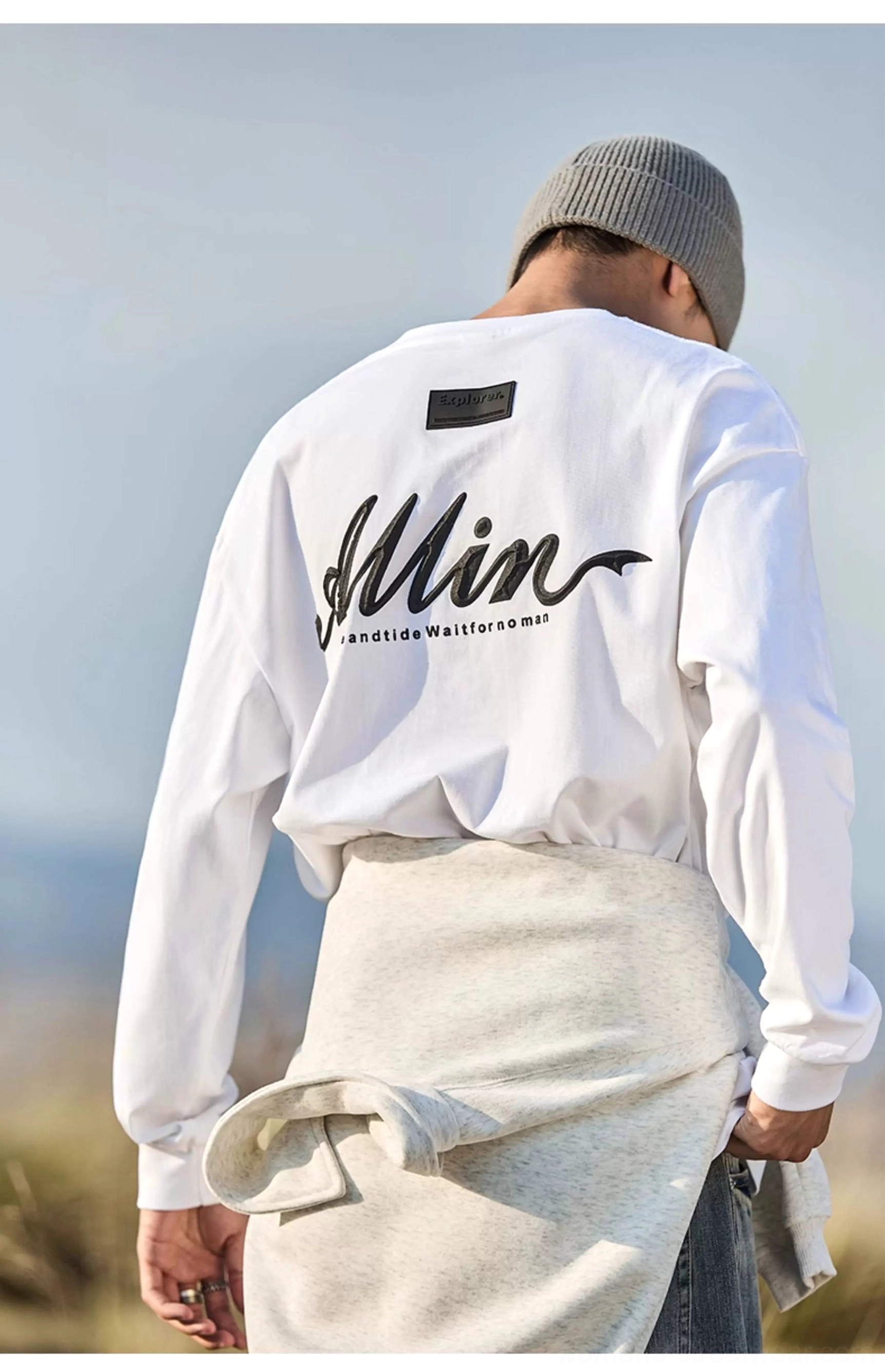 Ivory white graphic long sleeve streetwear tee showing relaxed drop shoulder fit and alpine script back print
