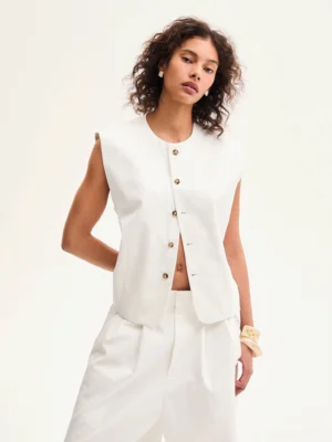 Front close up of an ivory white cotton sleeveless vest with crew neckline, exposed button placket, and minimalist Korean streetwear design
