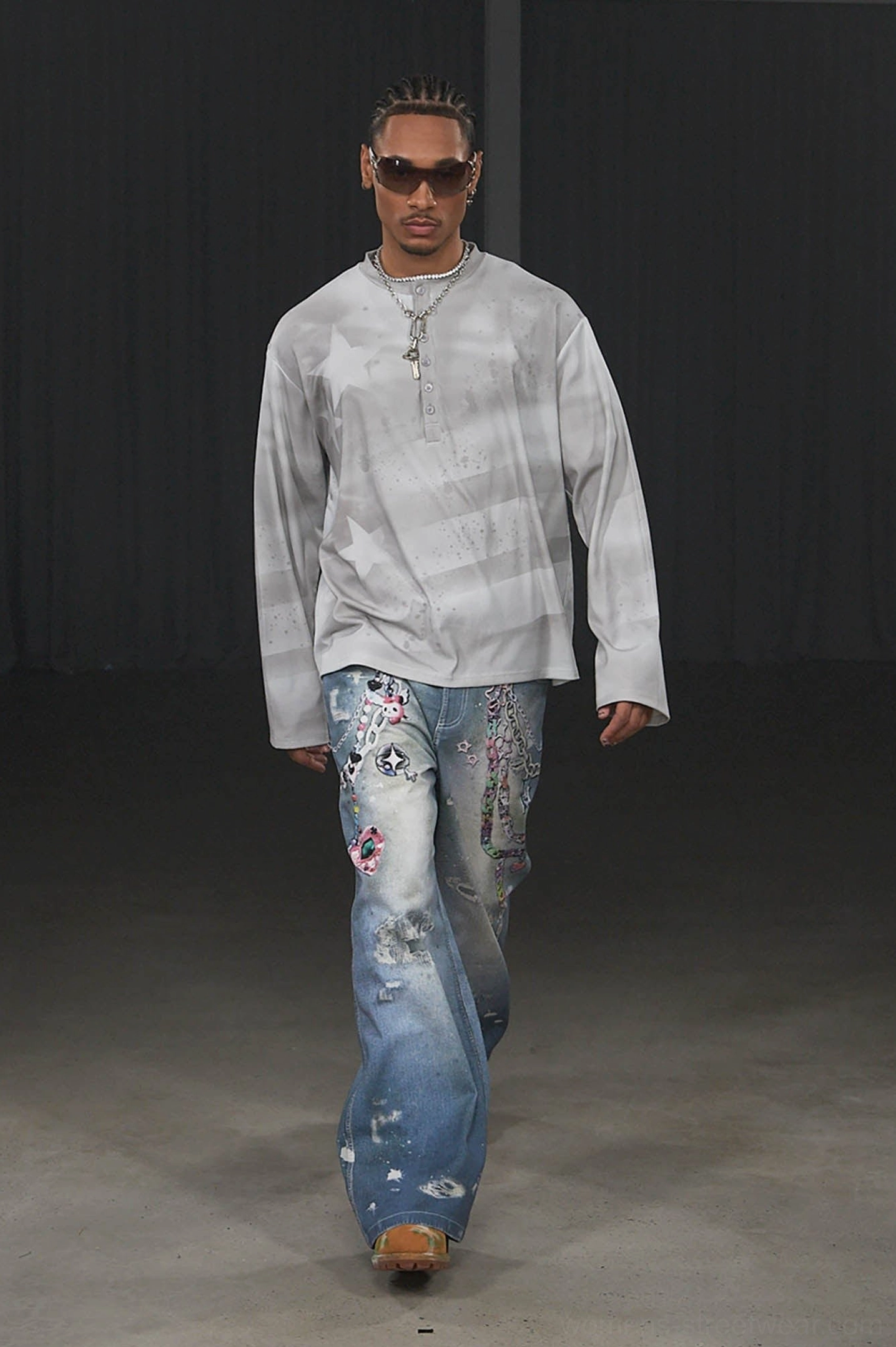 Full front walking view of male model wearing Kawaii chain wide-leg jeans with faded denim graphics and Y2K streetwear styling