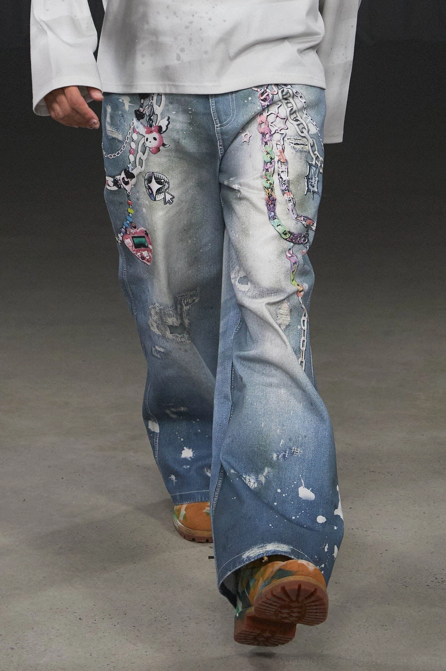 Front three-quarter view of Kawaii light blue wide-leg jeans with cartoon prints chain decorations distressed patches and casual streetwear shoes