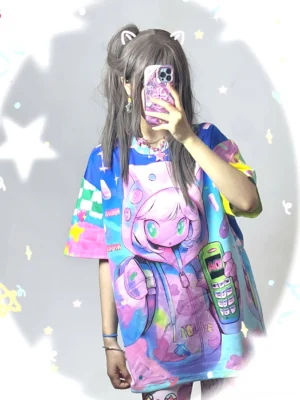 Model wearing a kawaii retro phone oversized graphic T-shirt with pastel tie dye colors, anime cat ear character artwork, checkered sleeve accents, and Y2K streetwear styling