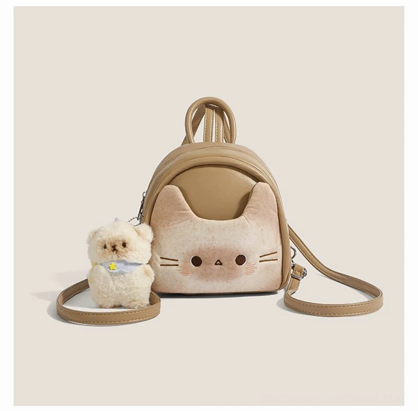 Front view of a kawaii toast beige cat face backpack with tan and off-white details, sturdy zipper hardware, and fluffy puppy ornament with yellow star scarf