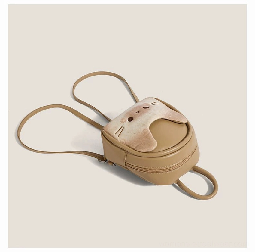 Overhead flat lay of a compact kawaii cat mini backpack showing the toast beige body, cat face panel, dual adjustable shoulder straps, and small everyday size
