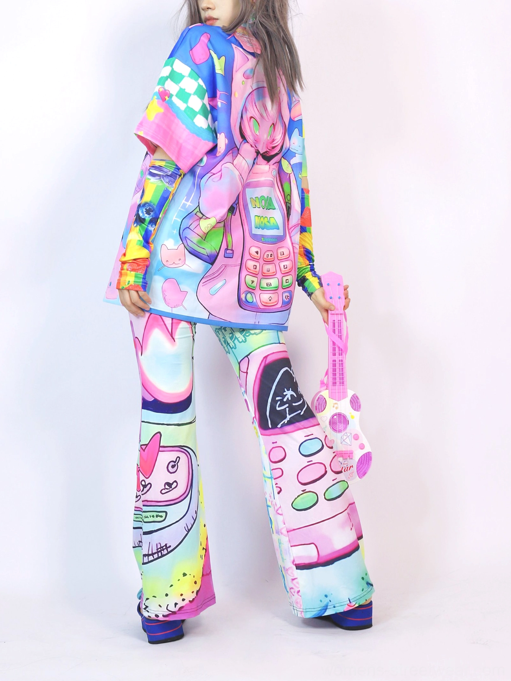 Side view of a colorful kawaii Y2K streetwear outfit with oversized retro phone graphic T-shirt, printed flare pants, cute cartoon electronics, and pink toy guitar