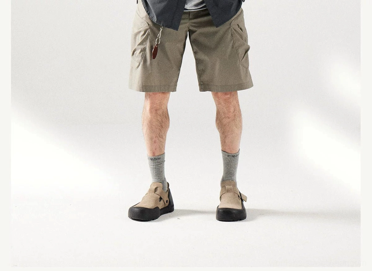 Front view of khaki cargo shorts with loose straight legs, metal waist detail, and classic outdoor utility styling