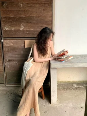 Khaki crinkled slip maxi dress with relaxed draped silhouette shown from the side with canvas tote bag