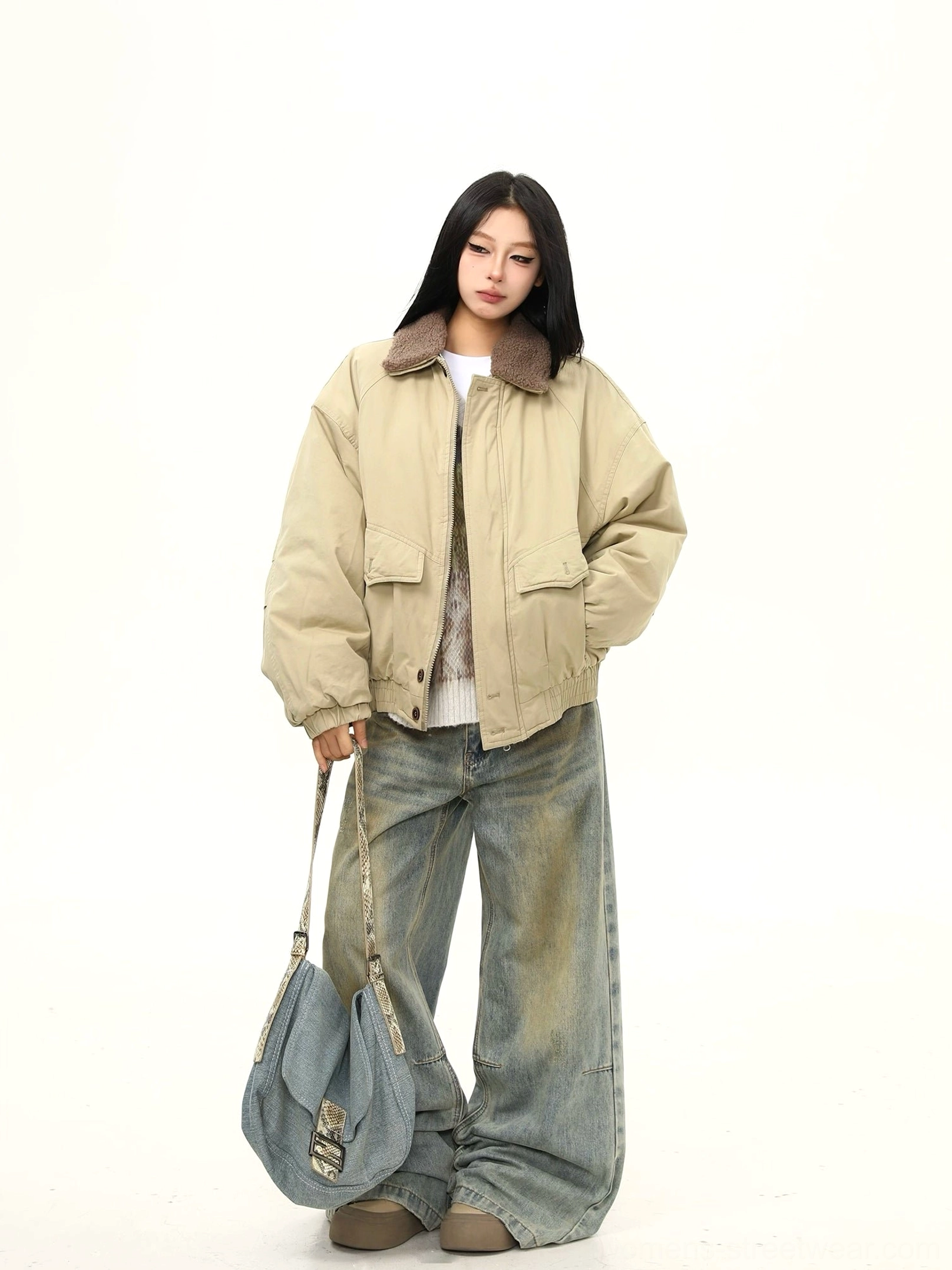 Full body side view of a relaxed khaki sherpa collar bomber jacket with cropped length, loose fit, and denim shoulder bag