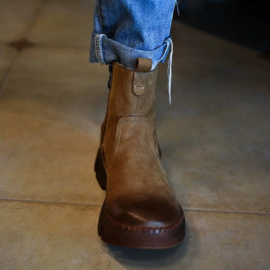 Close on-foot view of khaki fur-lined platform winter boots with distressed leather texture, side zipper, thick sole, and rolled denim