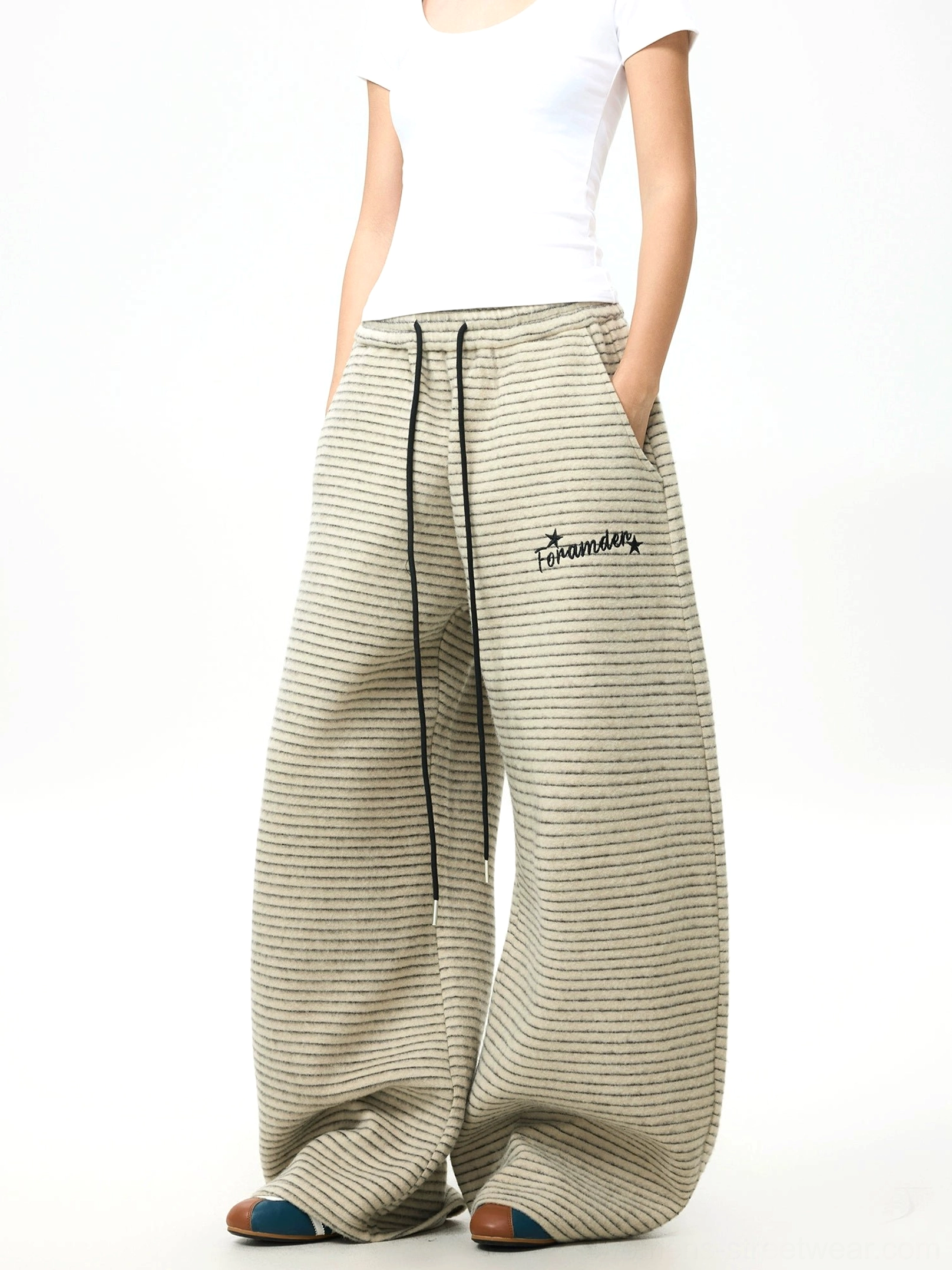 Side view of khaki gray striped fleece wide-leg streetwear pants showing relaxed drape, side pocket, and thigh embroidery