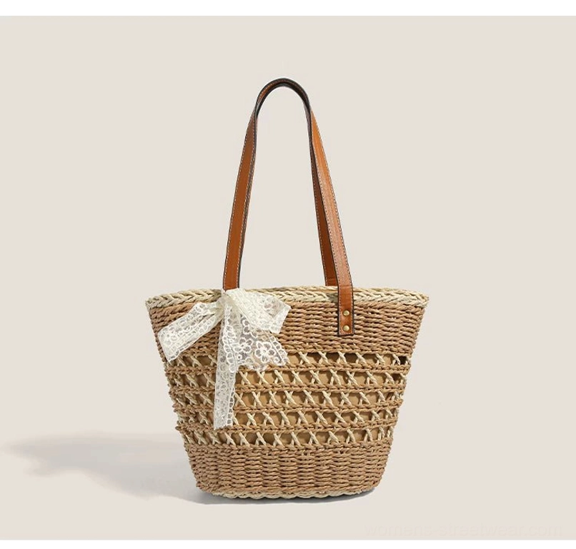 Close front view of khaki natural woven basket tote with prominent white lace bow and compact structured summer design