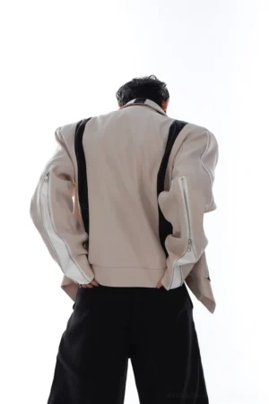 Rear view of khaki layered biker jacket showing decorative back leather straps, solid khaki back panel, oversized fit, and zippered sleeve details