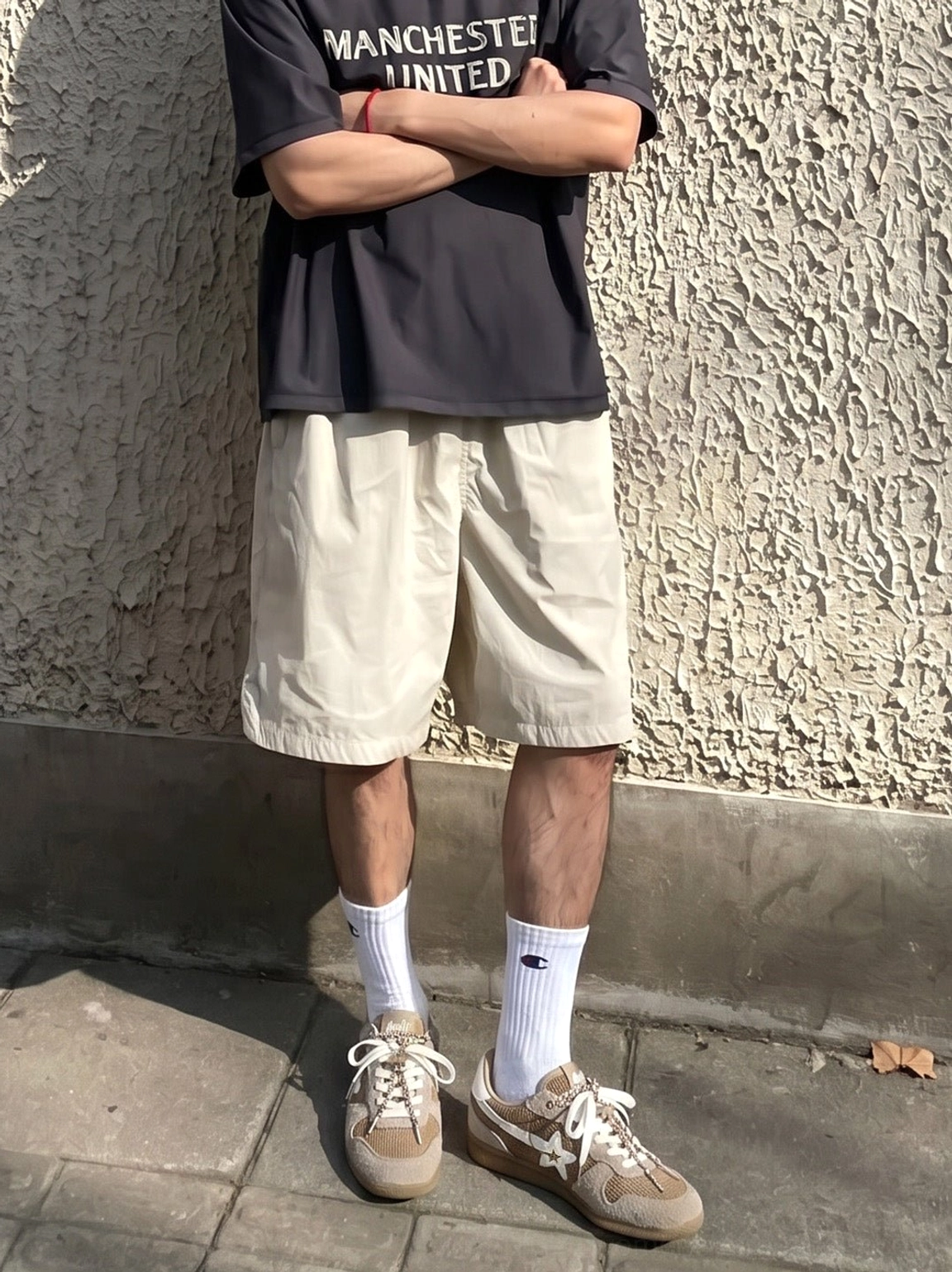 Male model wearing khaki mesh star German trainer sneakers with white socks and casual sportswear by a street wall