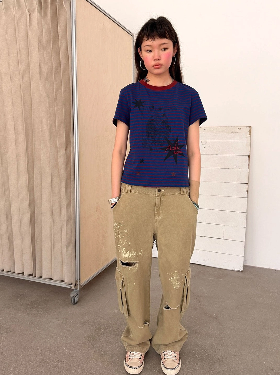 Khaki paint-splattered distressed cargo pants with vintage wash, wide legs, ripped details, and multiple utility pockets