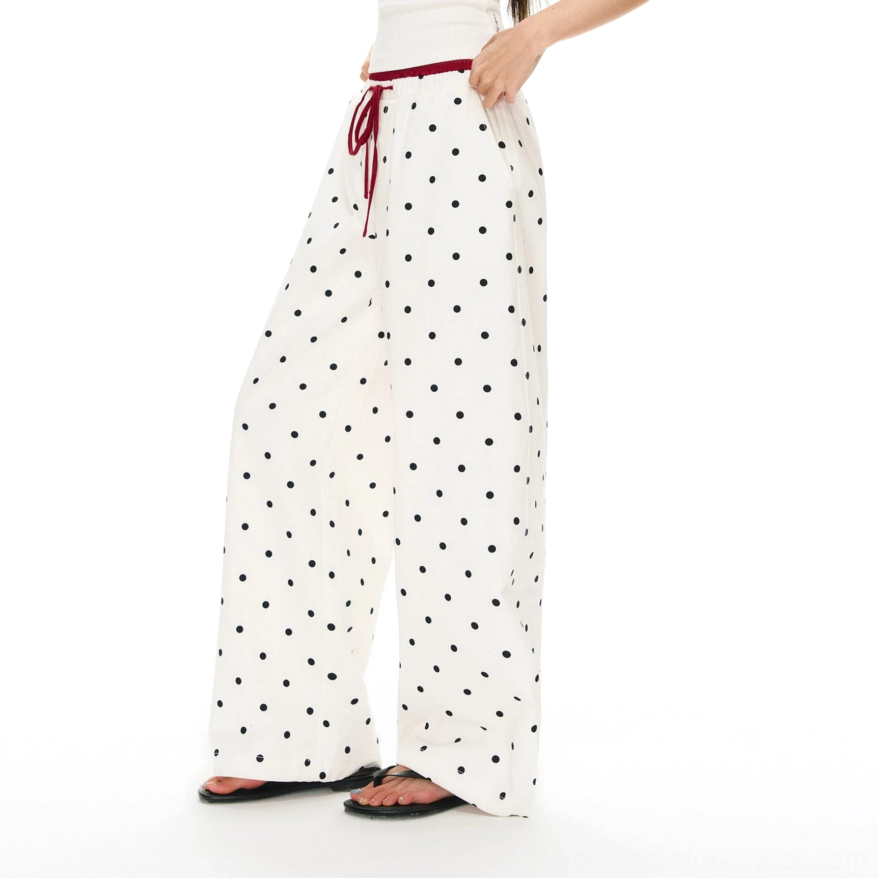 Khaki polka dot streetwear pants shown from a low side angle with practical side pocket, drawstring waist, and black slide sandals