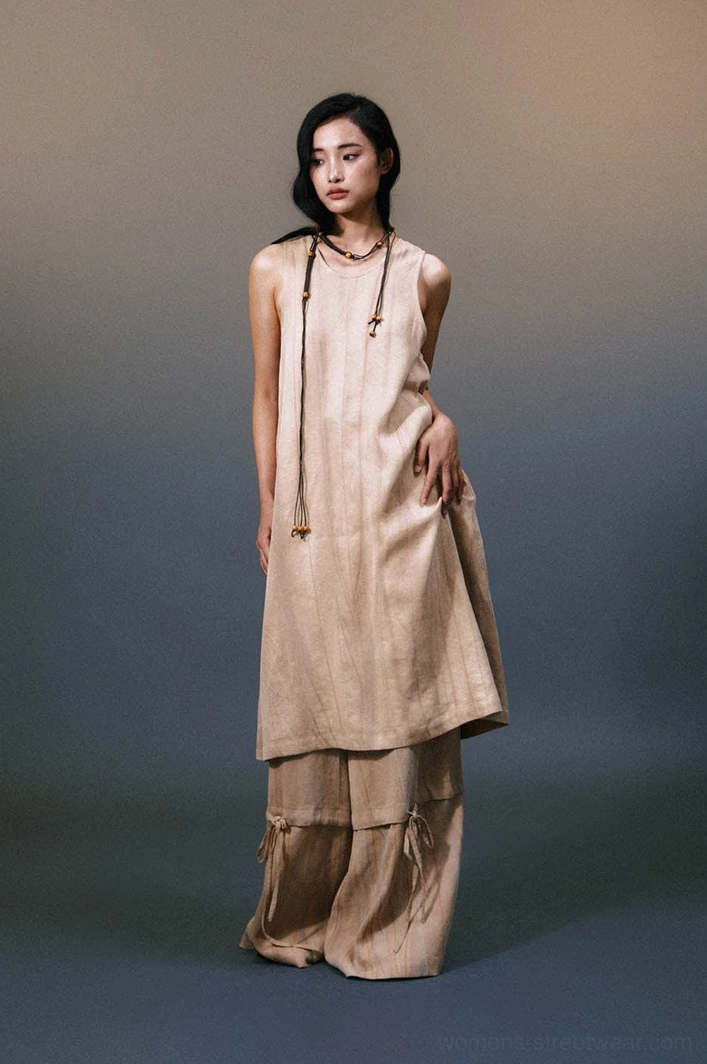 Side view of khaki sleeveless linen maxi dress showing relaxed drape, floor-length silhouette, and bead neck detail