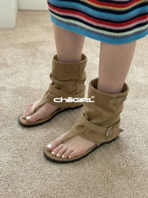 Top view of khaki slouchy thong toe suede sandal ankle boots worn with a striped mini skirt