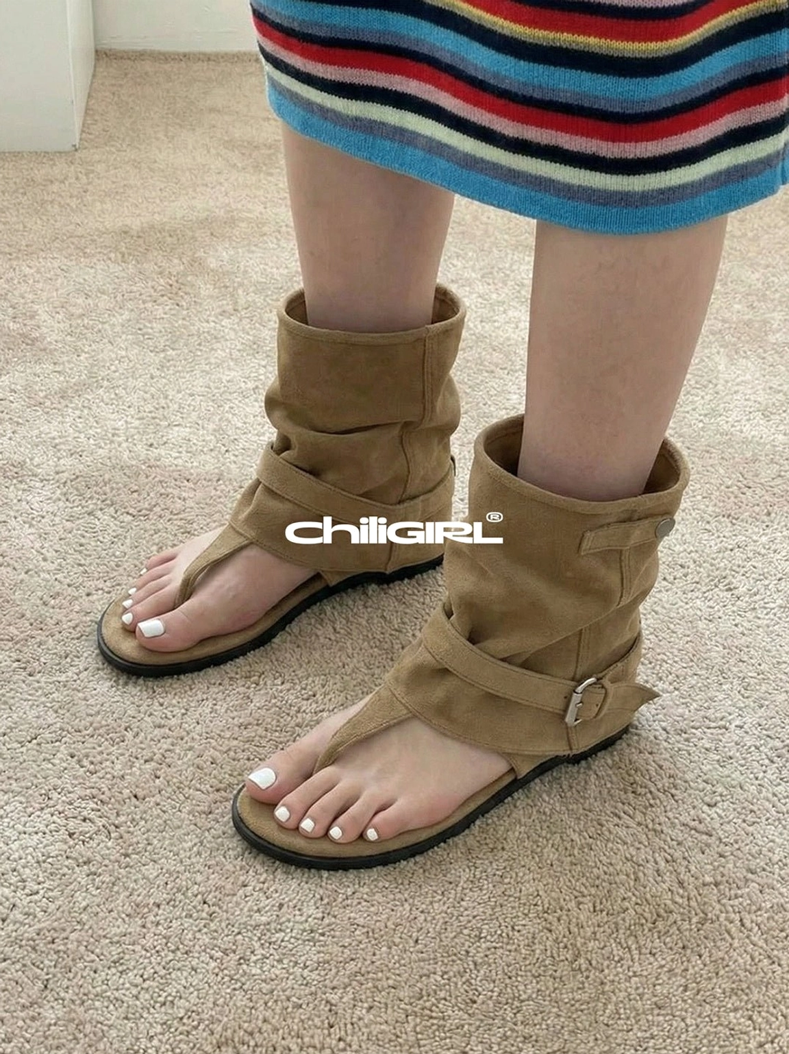 Top view of khaki slouchy thong toe suede sandal ankle boots worn with a striped mini skirt