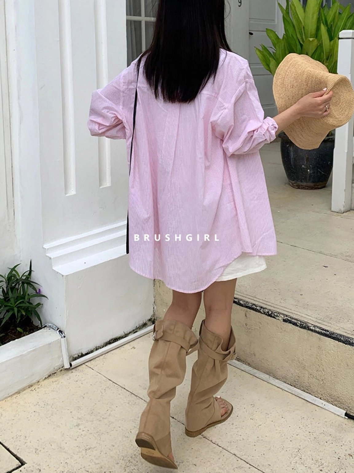 Full back view of a model wearing khaki slouchy western sandal boots with a loose pink button-down shirt
