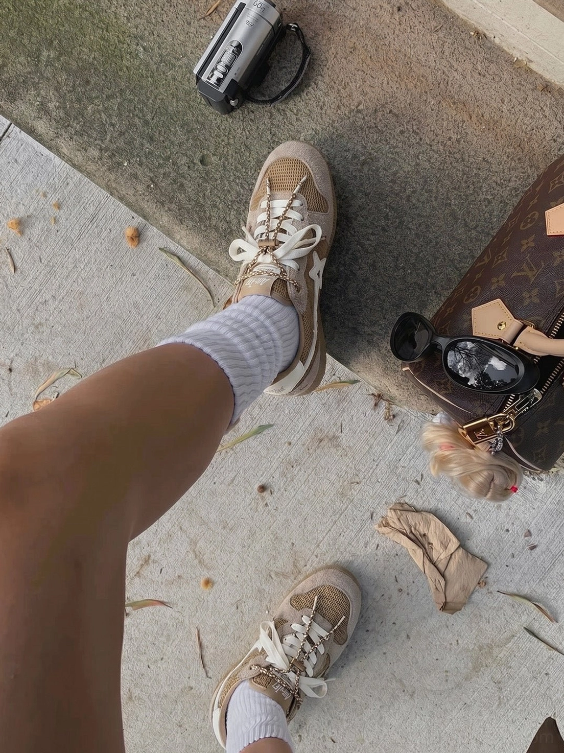 Top-down view of khaki star German trainer sneakers worn with casual streetwear on an outdoor sidewalk