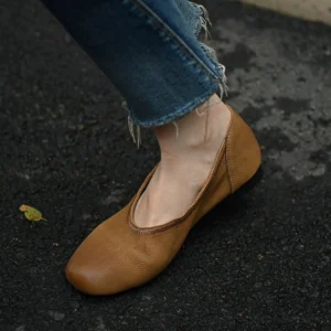 Khaki textured leather square-toe ballet flats worn with frayed cropped jeans on outdoor pavement side view