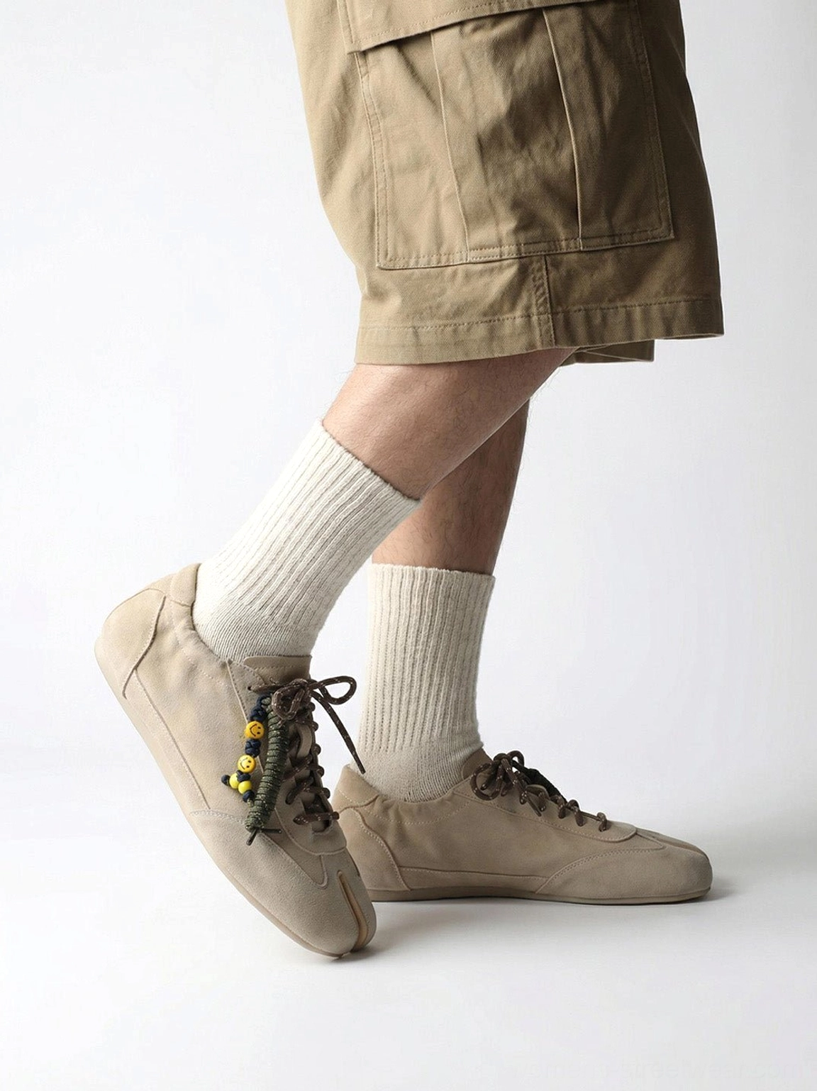 Side view of khaki thin-sole tabi sneakers worn with khaki cargo shorts and crew socks