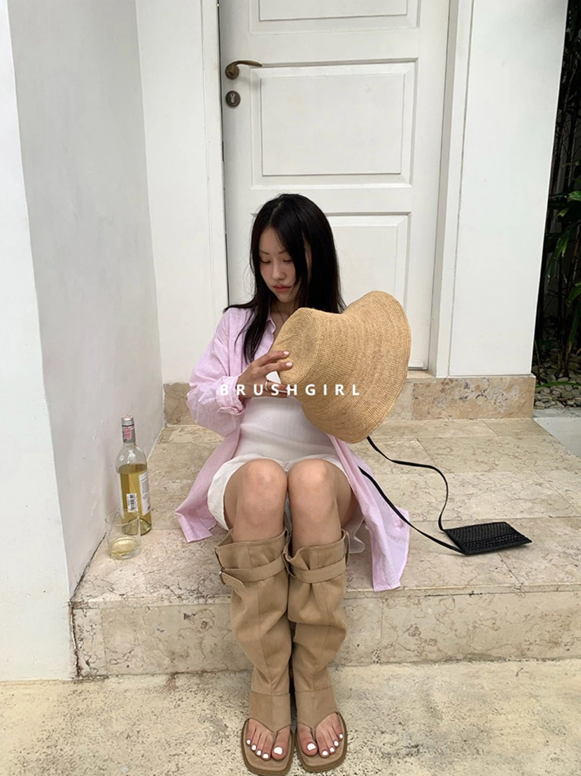 Female model wearing khaki thong knee-high sandal boots with white shorts and a casual western streetwear outfit