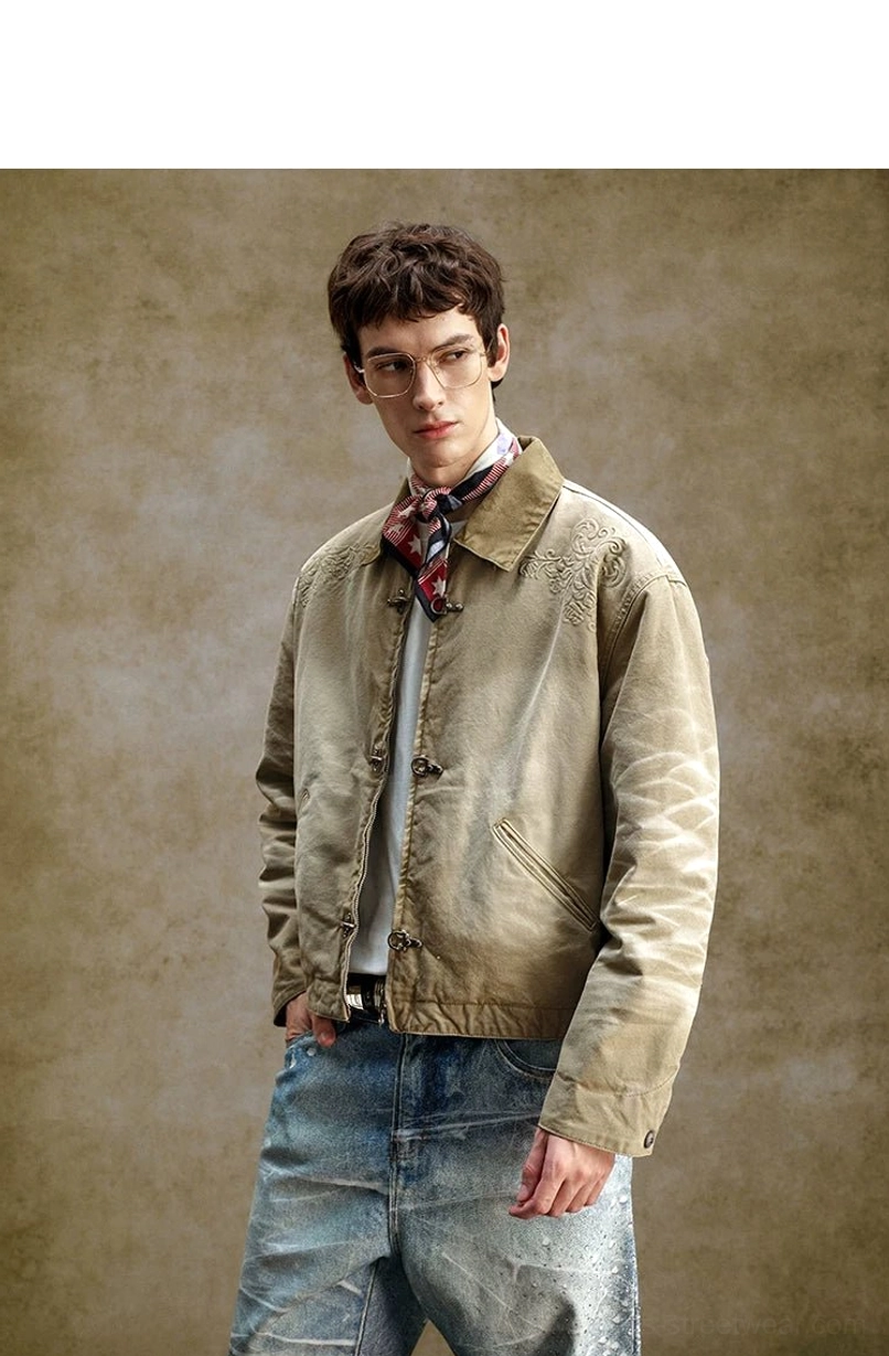 Three-quarter view of khaki utility work jacket with metal toggle closures, subtle shoulder embroidery, side pockets, and relaxed fit
