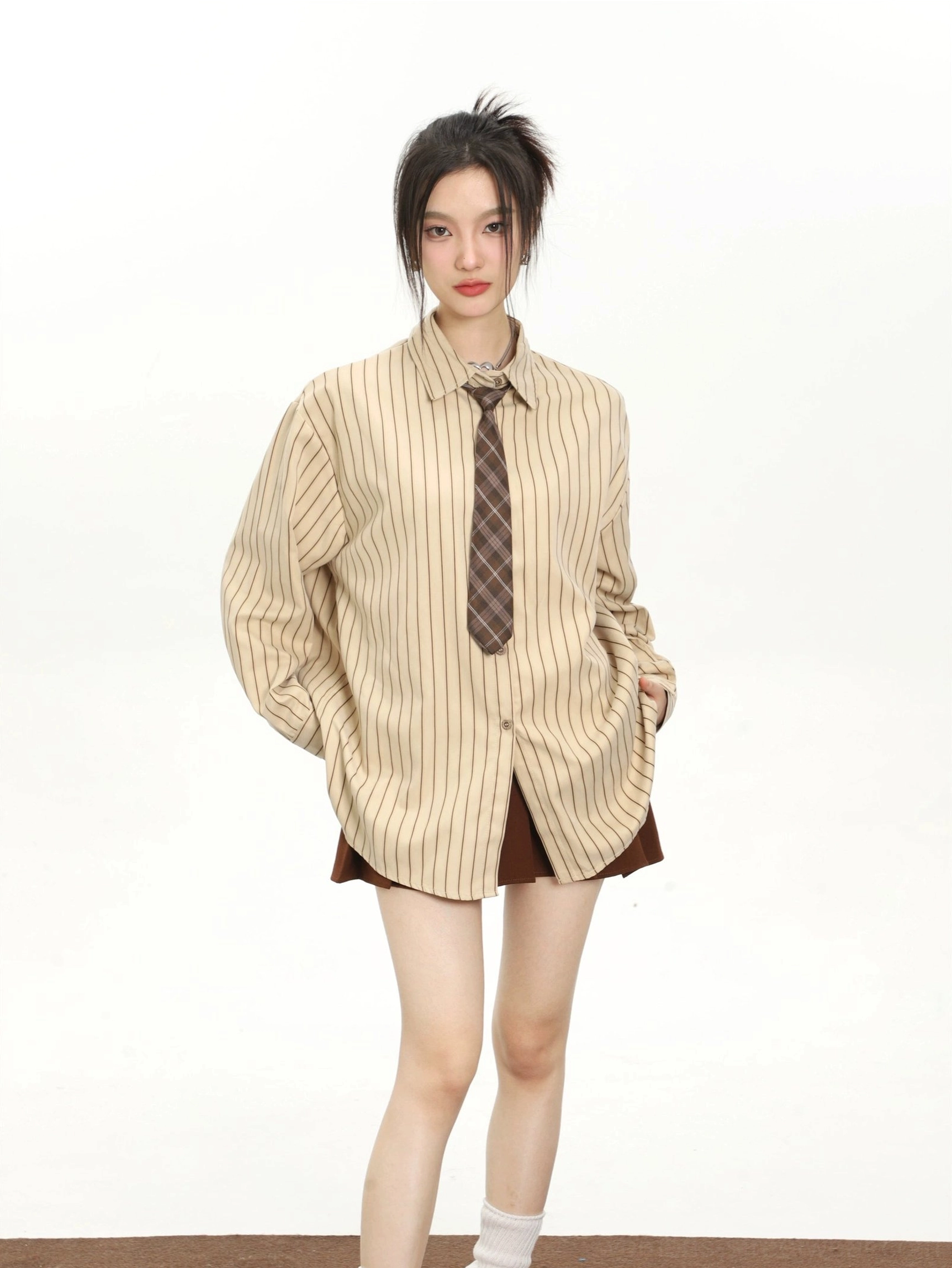 Khaki vertical striped loose fit women's shirt styled with brown mini shorts in a minimalist streetwear look