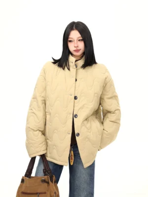 Khaki wavy quilted stand-collar padded jacket with oversized cocoon silhouette styled with wide-leg jeans and brown suede tote bag