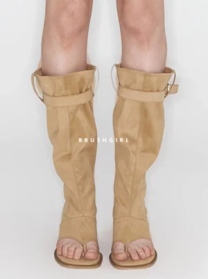 Front view of khaki knee-high thong sandal boots worn with a relaxed slouchy shaft and flat sole