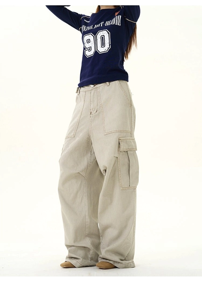 Front view of khaki full-length wide-leg cargo pants styled with a navy graphic long-sleeve top