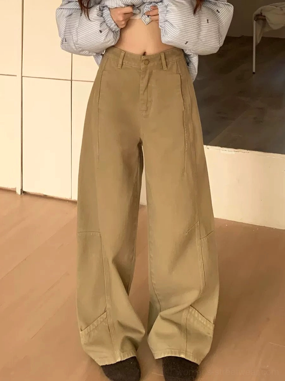 Close-up view of khaki wide-leg jeans featuring a natural-rise waist, button closure, paneled legs, and loose streetwear fit
