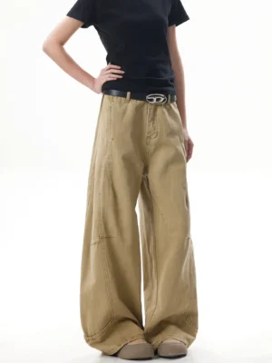 Front three-quarter view of khaki wide-leg streetwear pants with curved panel seams, high waist, vintage washed finish, black belt, and chunky brown shoes