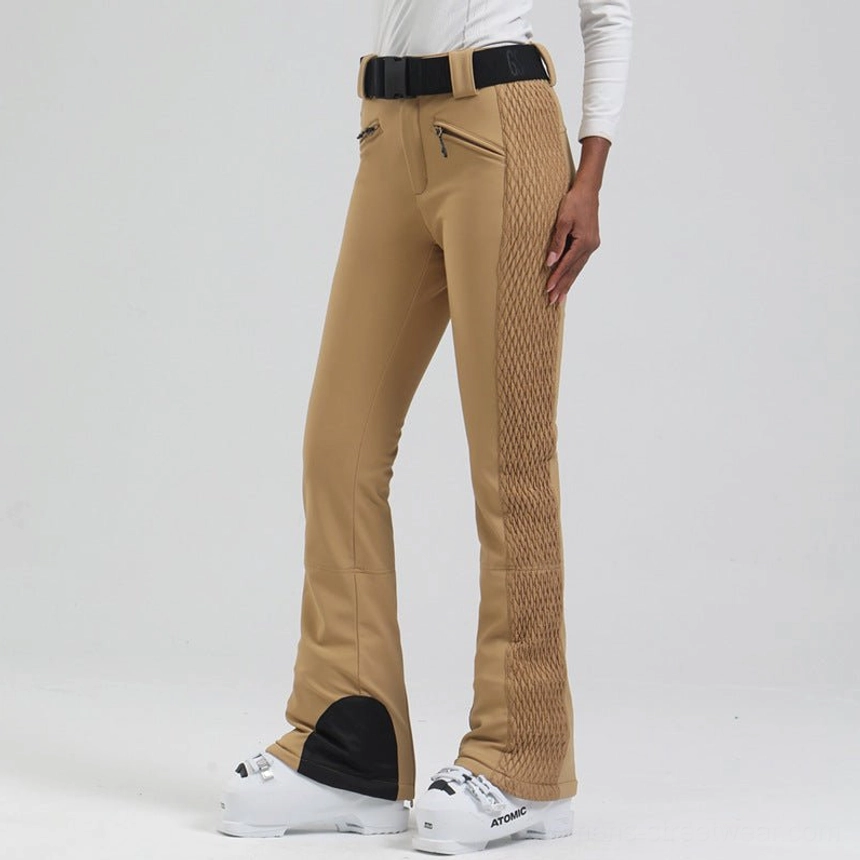 Low angle side view of khaki women's flared ski pants with quilted outer panels, black heel guards, and adjustable belt