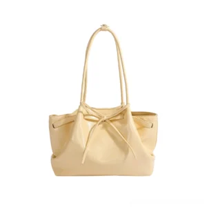 Cream yellow Korean bow cinch shoulder tote bag in glossy PU leather front studio view